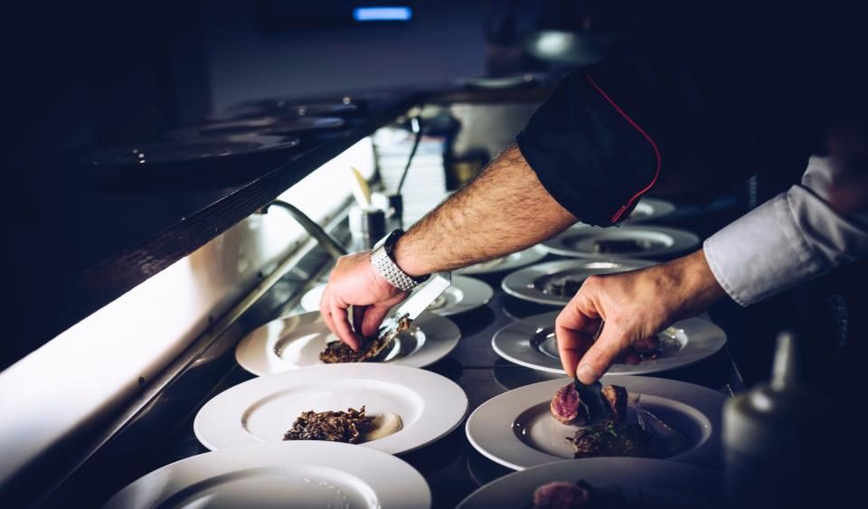 Le chef qui dresse les assiettes au pass de la cuisine